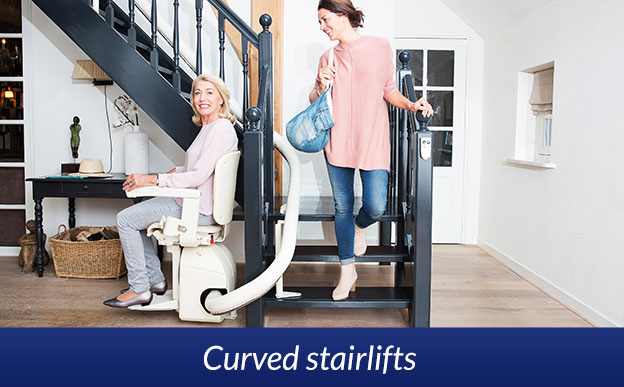 Stairlift with woman seated on curved staircase